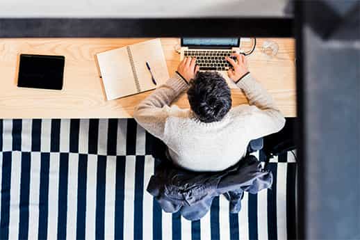 overhead view of a professional working at a laptop with a pen and notebook on the desk
